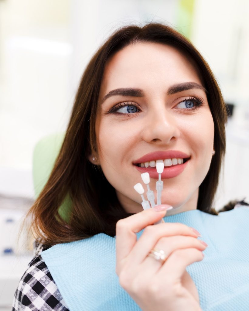 Girl chooses color of veneers at the dentist office